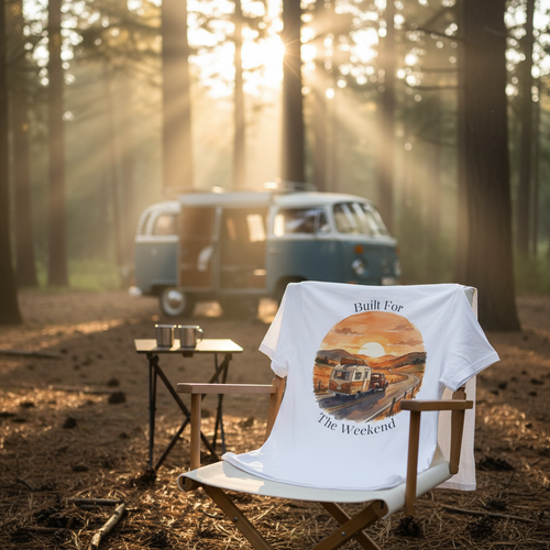Camper Van tee draped over a camp chair at a campsite with a vintage camper van in morning light